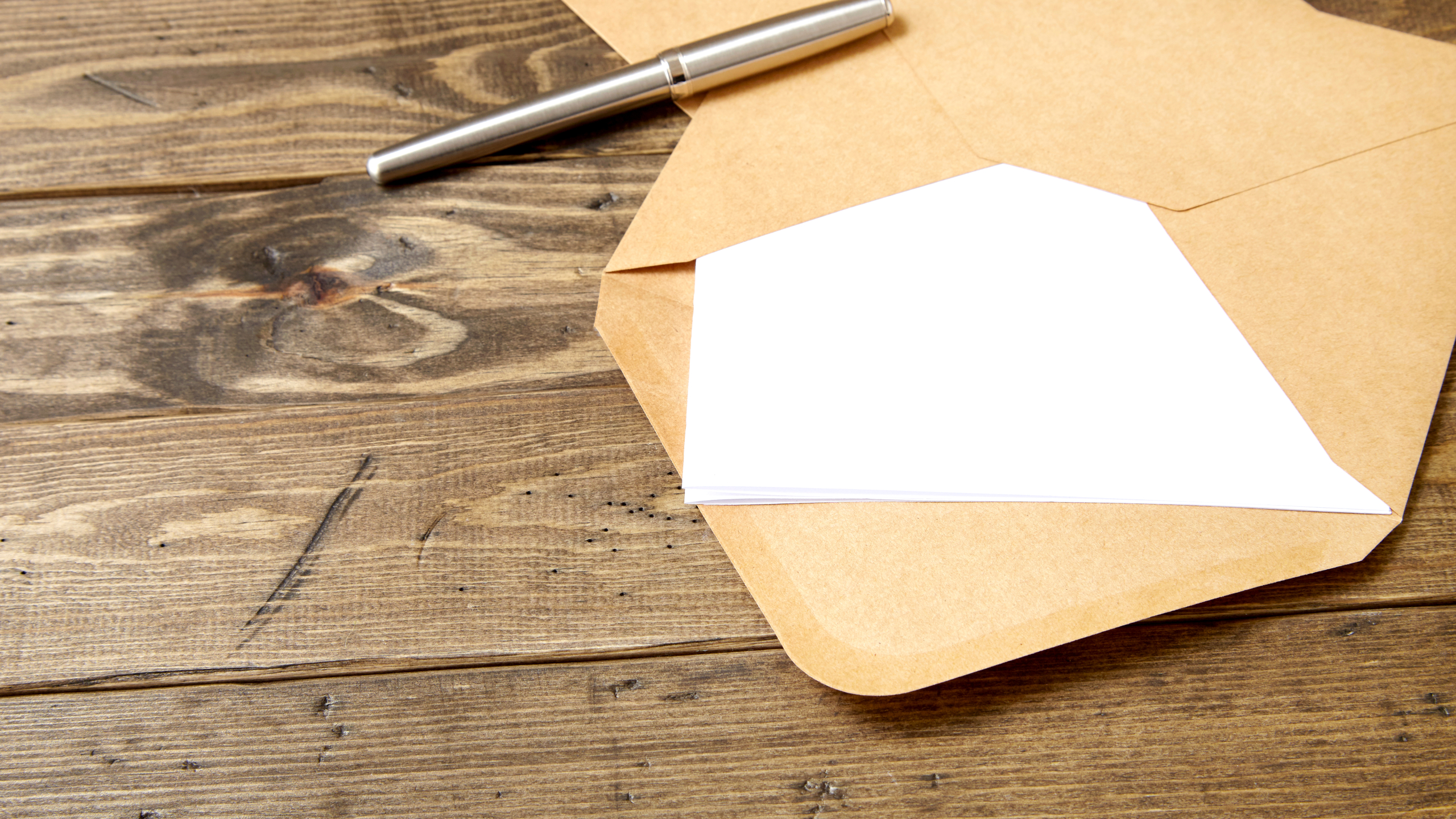 An open brown envelope with letter and writing pen on a rustic w